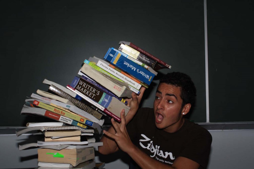 Joshua Rodrigez, communications junior, gets crushed by textbooks. Many students  use alternative methods to buying textbooks such as renting, sharing, or avoiding them altogether. Photo by Zach Schoenheide