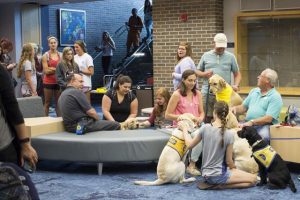 Students take advantage of the “PAWS Your Stress” event while others wait for a turn to pet and play with the service dogs in-training from Canine Companions.  Photo by Michael Herrera