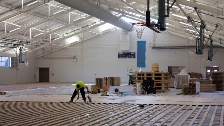 A construction worker installs flooring in the new Field House facility. 
Photo by Michael Herrera