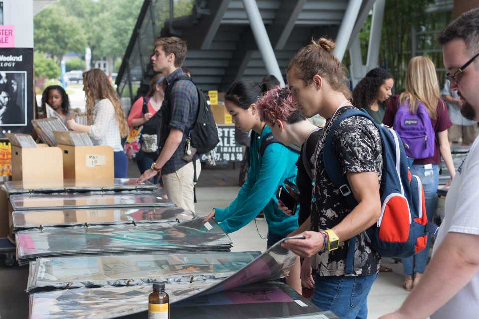 Students flip through giant books of posters. Photo by Michael Herrera
