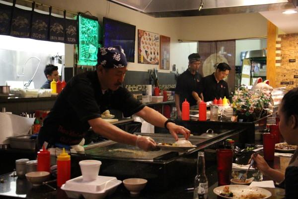 A cook serves food fresh off the grill to customers after preparing their entrees. Photo by Courtney Stringfellow. 