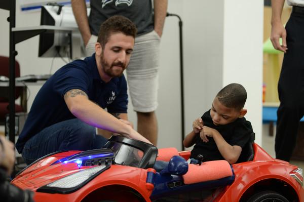 Student shows Maddex, a five-year-old with cerebral palsy, how to use the joystick in order to drive the car. (Courtesy of Joanna Norris)