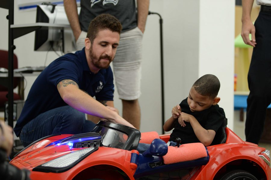 Student shows Maddex, a five-year-old with cerebral palsy, how to use the joystick in order to drive the car.  (Courtesy of Joanna Norris)