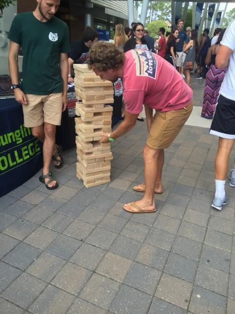 UNF student plays Jumbo Jenga by Greek life tables. Photo by Audrey Carpenter