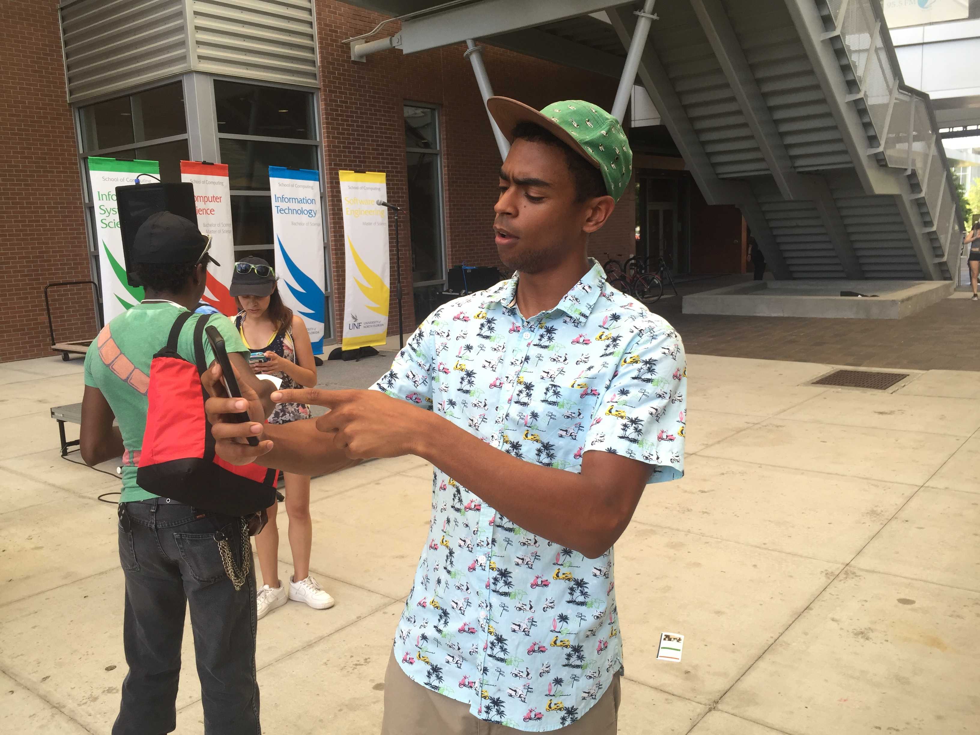 Andrew Baker points out pokestops on the Pokemon Go app. Photo by Audrey Carpenter