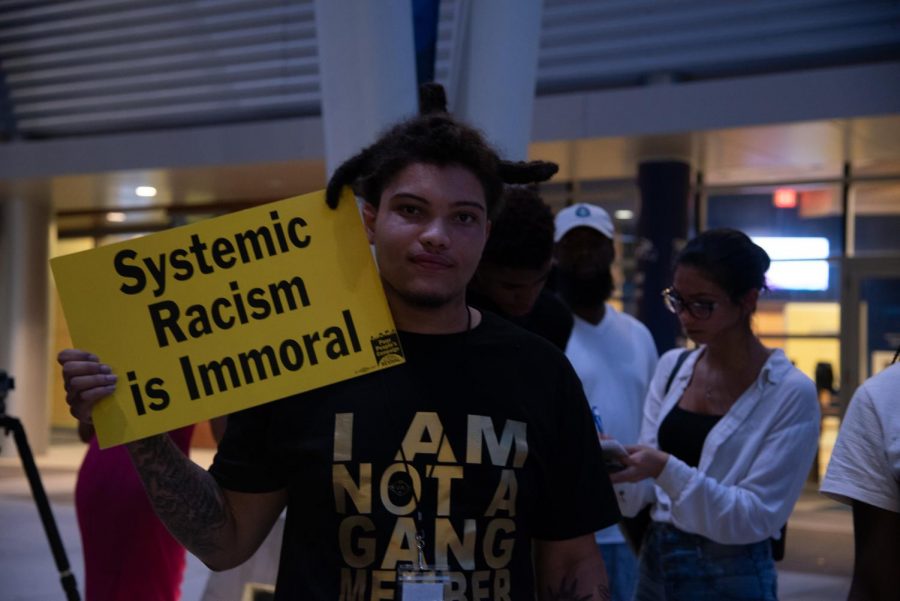 Dequan Frank with a "Systemic Racism is Immortal" sign at the vigil.