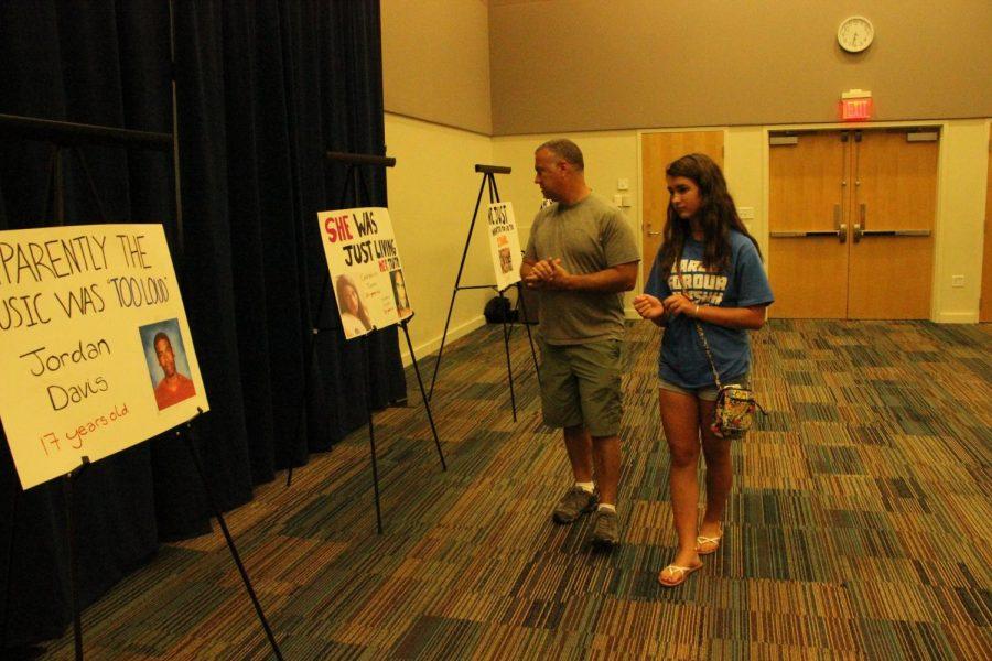 Town Hall attendees looking at posters of people who fell victim to gun violence. 