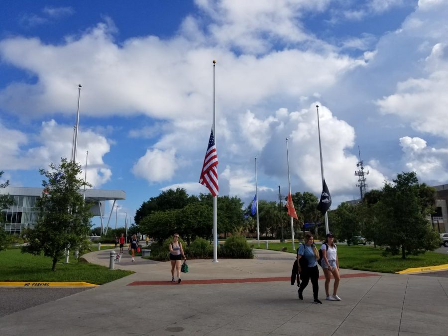 Students walk by UNFs flags held at half-staff. Photo by Sam Chaney.