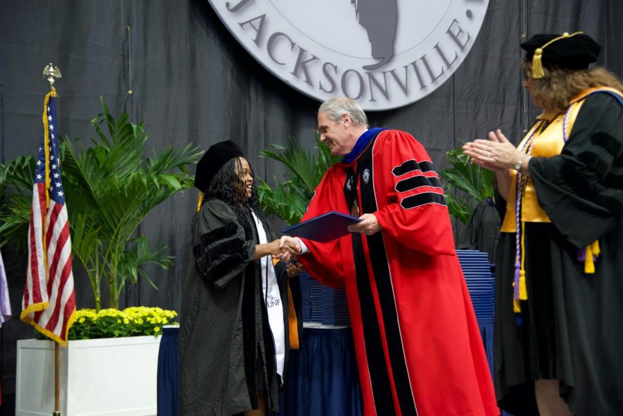 A graduate receiving her degree before walking across the stage.