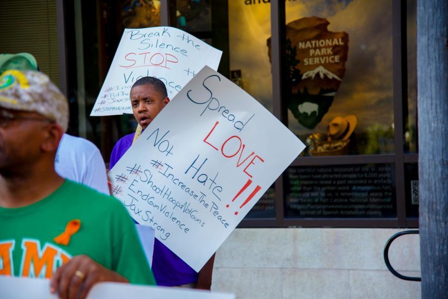 Peaceful protester holds sign stating "Spread Love Not Hate".