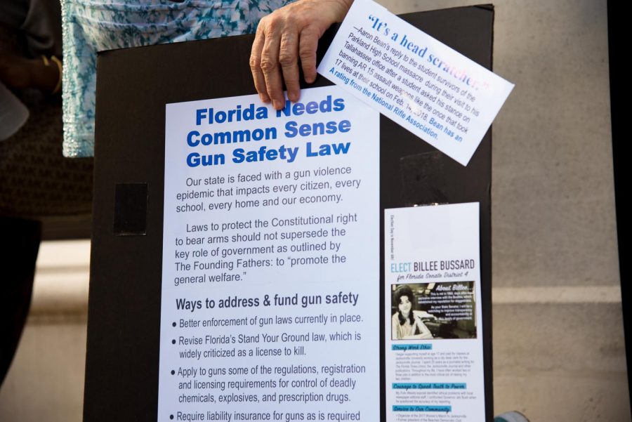 Attendee holds poster saying "Florida Needs Common Sense Gun Safety Laws".