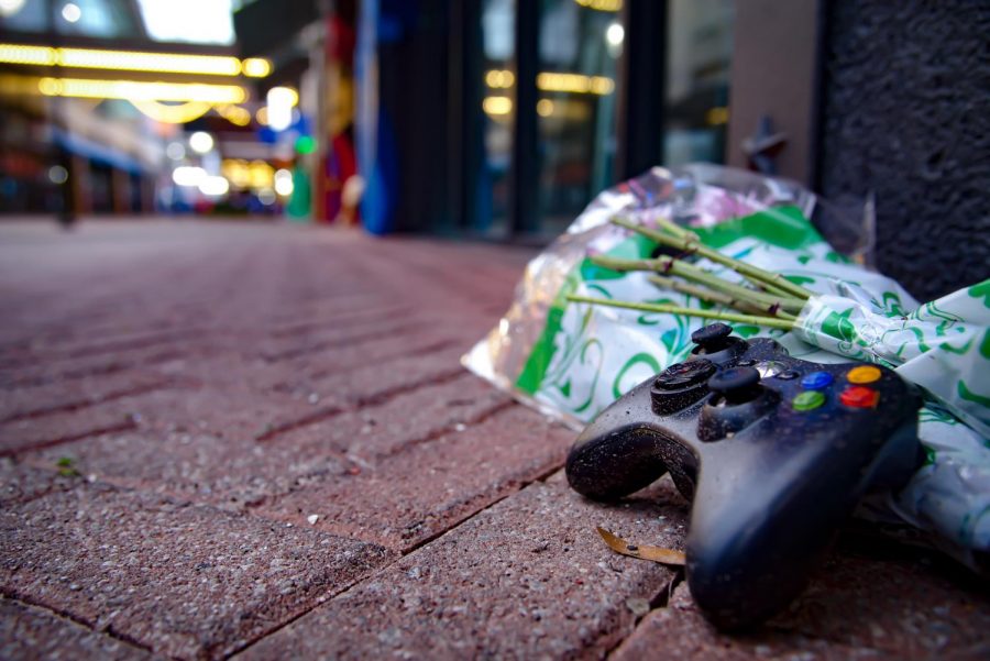 Game controller and flowers placed outside of Chicago Pizza in remembrance of the lives lost in The Landing shooting.