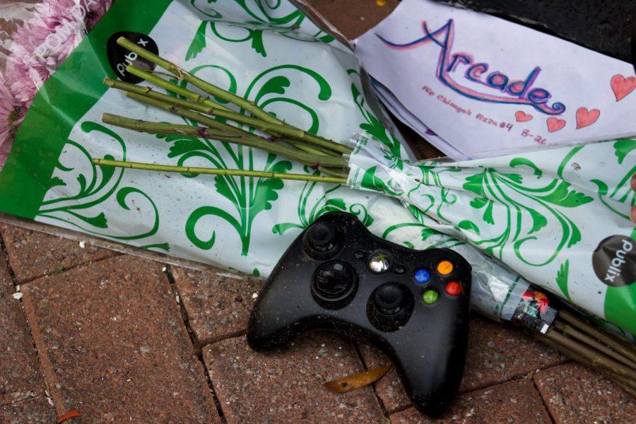 Flowers and game controller place outside Chicago Pizza in remembrance of the lives lost at The Landing shooting.