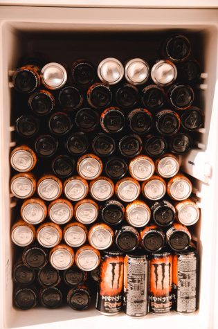 Multiple cans of Monster energy drinks in a fridge.