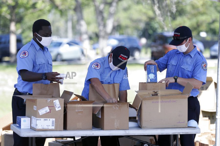 Members of Orange County Fire Rescue pack personal protective equipment (PPE) items including disposable face masks, reusable masks and hand sanitizer in bags to be handed out to small businesses, Wednesday, June 24, 2020, in Orlando, Fla. Because of the coronavirus pandemic, Orange County hopes to supply up to 10,000 businesses with the items over the next several days. (AP Photo/John Raoux)