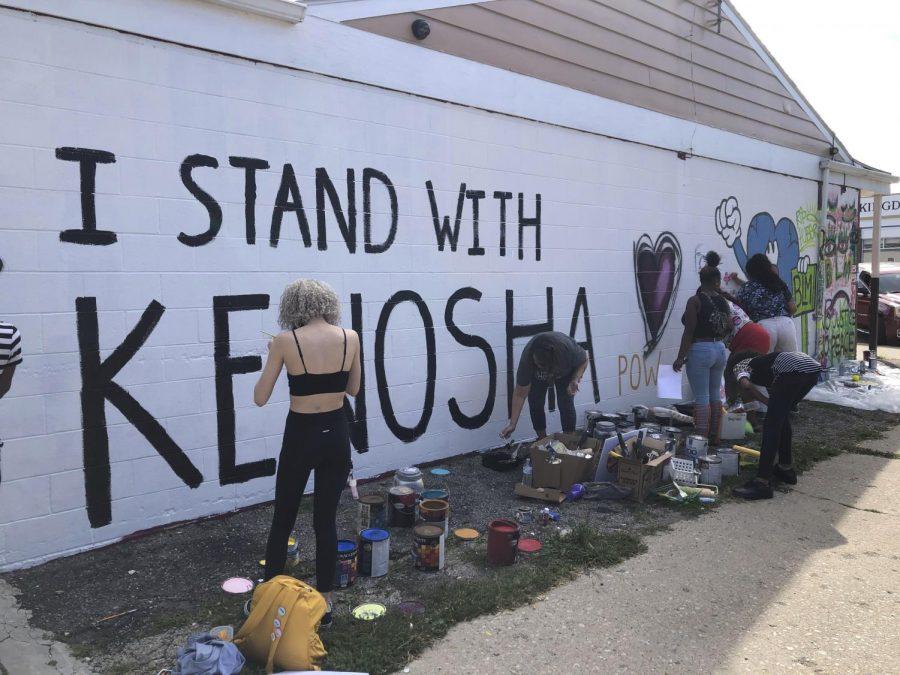 Volunteers paint murals on boarded-up businesses in Kenosha, Wis., on Sunday, Aug. 30, 2020, at an Uptown Revival. The event was meant to gather donations for Kenosha residents and help businesses hurt by violent protests that sparked fires across the city following the police shooting of Jacob Blake. (AP Photo/ Russell Contreras)