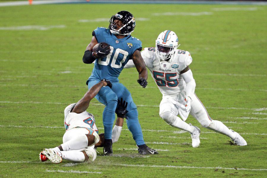 Jacksonville Jaguars running back James Robinson, center, looks for a way to get past Miami Dolphins outside linebacker Elandon Roberts, left, and outside linebacker Jerome Baker (55) during the second half of an NFL football game, Thursday, Sept. 24, 2020, in Jacksonville, Fla. (AP Photo/Stephen B. Morton)