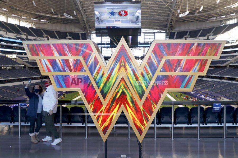 A pair of fans take a photo as they stand by a sculpture in the shape of the "Wonder Woman" logo on the main concourse of AT&amp;T Stadium before an NFL football game between the San Francisco 49ers and Dallas Cowboys in Arlington, Texas, Sunday, Dec. 20, 2020. (AP Photo/Michael Ainsworth)