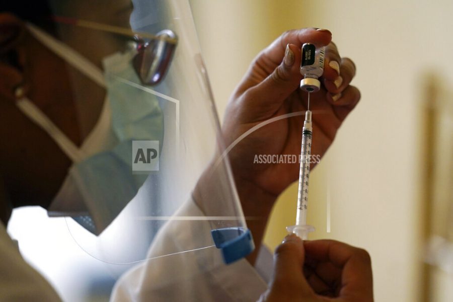 FILE - In this Tuesday, Jan. 12, 2021 photo, a pharmacist with Walgreens Pharmacy prepares a syringe with the Pfizer-BioNTech COVID-19 vaccine for residents and staff at the The Palace assisted living facility in Coral Gables, Fla. Florida was one of the first states to throw open vaccine eligibility to members of the general public over 65, leading to rumors that tourists and day-trippers are swooping into the state solely for the jab.   Gov. Ron DeSantis said stories of the rich flying to Florida, getting vaccinated and returning home are overblown.  (AP Photo/Lynne Sladky, File)