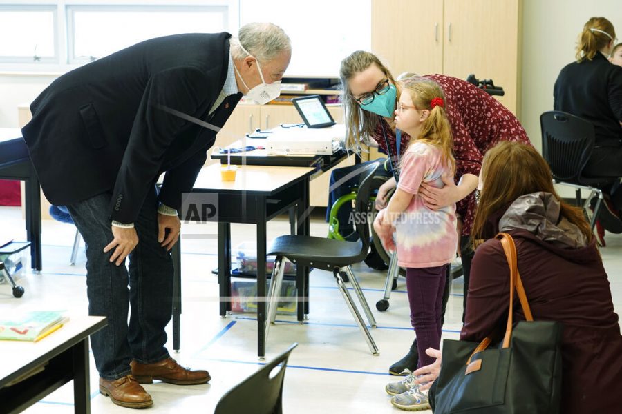 Washington Gov. Jay Inslee, left, talks with a student as teacher Alyson Lykken, center, looks on, Tuesday, Feb. 2, 2021, during a visit to a low-incidence disability classroom at Elk Ridge Elementary School in Buckley, Wash. The school has had some students in classrooms for in-person learning since September of 2020, but other students who attend the school are still learning remotely. Inslee visited the school to observe classrooms and take part in a discussion with teachers and administrators about plans to further open in-person learning in Washington in the future. (AP Photo/Ted S. Warren)