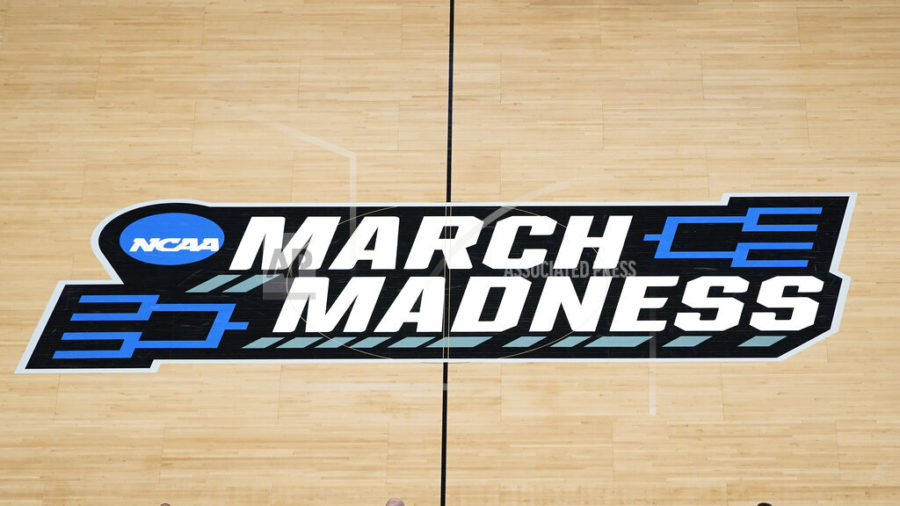 FILE - In this March 20, 2021, file photo the March Madness logo is shown on the court during the first half of a mens college basketball game in the first round of the NCAA tournament at Bankers Life Fieldhouse in Indianapolis. A Supreme Court case being argued this week amid March Madness could erode the difference between elite college athletes and professional sports stars. (AP Photo/Paul Sancya, File)