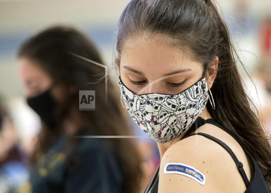 Kent State University student Regan Raeth of Hudson, Ohio, looks at her vaccination bandage as she waits for 15 minutes after her shot in Kent, Ohio, Thursday, April 8, 2021. U.S. colleges hoping for a return to normalcy next fall are weighing how far they should go in urging students to get the COVID-19 vaccine, including whether they should — or legally can — require it. (AP Photo/Phil Long)
