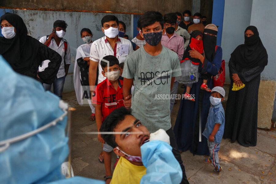 A health worker takes a mouth swab sample of a man to test for COVID-19 as others wait their turn to get tested at a hospital in Hyderabad, India, Monday, April 19, 2021. New infections are rising faster in India than any other place in the world, stunning authorities and capsizing its fragile health system. Overall, India has more than 15.6 million cases, the second-highest after the United States, with 182,553 deaths.(AP Photo/Mahesh Kumar A.)