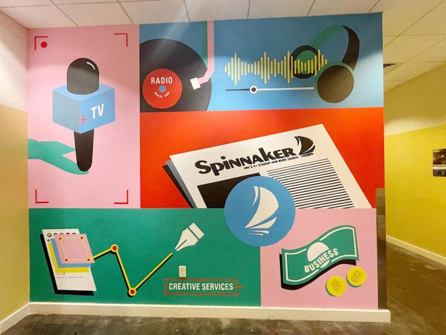 A mural painted on Spinnaker's front office wall, featuring colors of blue, red, green and pink with illustrations of newspapers, social media, radio waves and TV