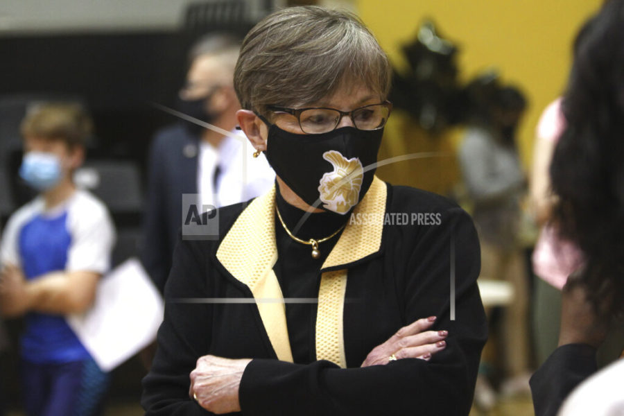 In this Monday, May 17, 2021, photo,  Kansas Gov. Laura Kelly tours a COVID-19 vaccination clinic for students aged 12 through 15 set up in a gym at Topeka High School in Topeka, Kan. The Democratic governor is under increasing pressure to end an extra $300 a week in benefits for unemployed workers, with critics of the aid arguing that businesses are having problems hiring enough workers because of it. (AP Photo/John Hanna)
