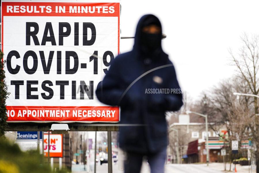 FILE - In this Jan. 25, 2021, file photo, a person wearing face mask as a precaution against the coronavirus walks near a sign advertising a rapid COVID-19 testing site in Philadelphia. U.S. healthy officials say that most fully vaccinated Americans can skip testing for COVID-19, even if they were exposed to someone infected.  (AP Photo/Matt Rourke, File)