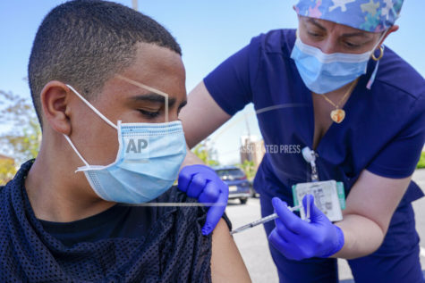 FILE In this May 14, 2021, file photo, Justin Bishop, 13, watches as Registered Nurse Jennifer Reyes inoculates him with the first dose of the Pfizer COVID-19 vaccine at the Mount Sinai South Nassau Vaxmobile parked at the De La Salle School in Freeport, N.Y. U.S. healthy officials say that most fully vaccinated Americans can skip testing for COVID-19, even if they were exposed to someone infected. (AP Photo/Mary Altaffer, File)