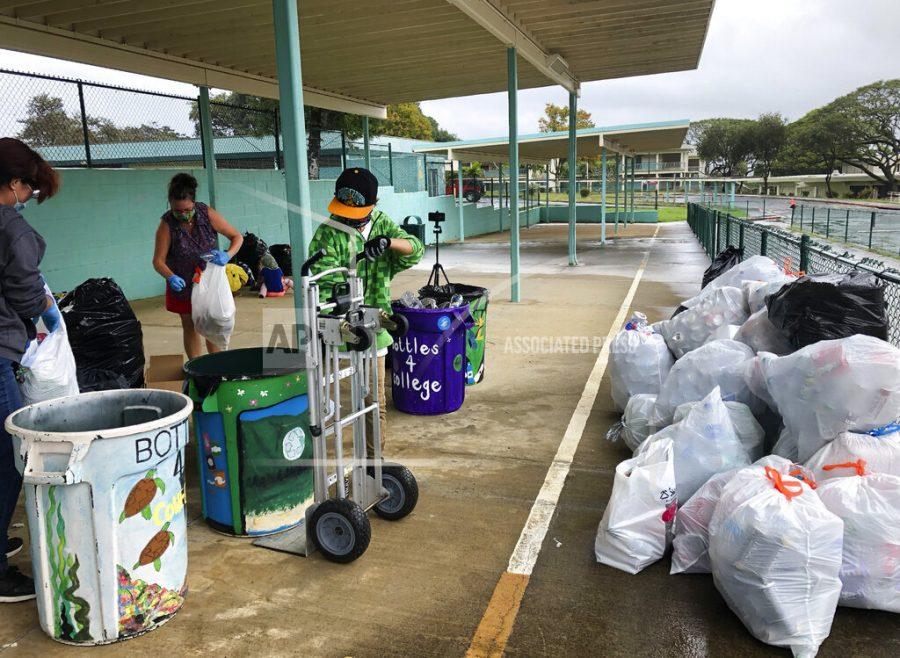 In this March 18, 2021, photo provided by Maria Price, Genshu Price, right, and other volunteers at S.W. King Intermediate School in Kāneohe, Hawaii, sort cans and bottles for Bottles4College, a recycling project he started that raises money for students college tuition. (Bottles4College via AP)