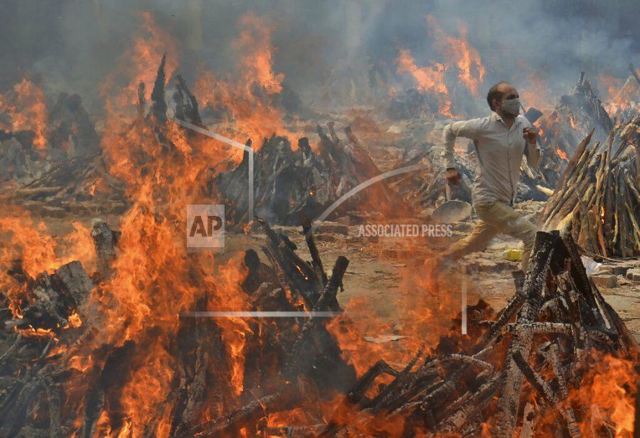 FILE - In this April 29, 2021, file photo, a man runs to escape heat emitting from the multiple funeral pyres of COVID-19 victims at a crematorium in the outskirts of New Delhi, India. Indias excess deaths during the pandemic could be a staggering 10 times the official COVID-19 toll, likely making it modern Indias worst human tragedy, according to the most comprehensive research yet on the ravages of the virus in the south Asian country. (AP Photo/Amit Sharma, File)