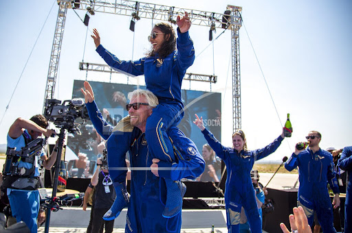 Virgin Galactic founder Richard Branson carries crew member Sirisha Bandla on his shoulders while celebrating their flight to space at Spaceport America near Truth or Consequences, N.M., Sunday, July 11, 2021. (AP Photo/Andres Leighton)