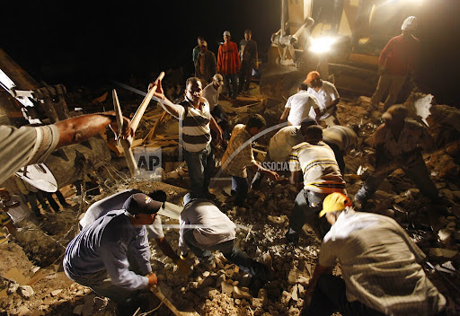 Rescuers work to free trapped survivors and find dead victims in a four story building that collapsed in the 7.0-magnitude earthquake in Port-au-Prince, Haiti, Wednesday, Jan. 13, 2010. (AP Photo/Gerald Herbert)