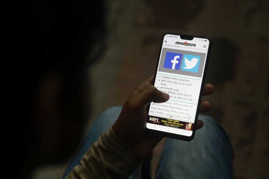 In this Dec. 20, 2018, file photo, a Bangladeshi reads a news report that makes mention of Facebook along with other social networking service, on his mobile phone in Dhaka, Bangladesh. (AP Photo, File)