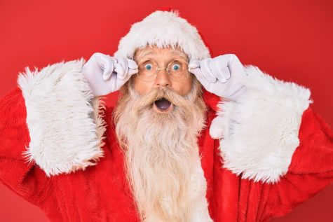 Santa Claus holding glasses afraid and shocked with surprise and amazed expression, fear and excited face.