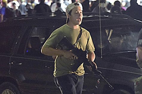 In this Aug. 25, 2020, file photo, Kyle Rittenhouse carries a weapon as he walks along Sheridan Road in Kenosha, Wis., during a night of unrest following the weekend police shooting of Jacob Blake. Rittenhouse is white. So were the three men he shot during street protests in Kenosha in 2020. But for many people, Rittenhouses trial will be watched closely as the latest referendum on race and the American judicial system. (Adam Rogan/The Journal Times via AP, File)