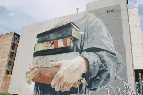 Mural of a person holding books. 