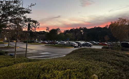 The sky glows a gorgeous rosy red as the sun disappears over the horizon of the Thomas G. Carpenter Library parking lot.