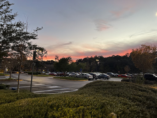 The sky glows a gorgeous rosy red as the sun disappears over the horizon of the Thomas G. Carpenter Library parking lot.