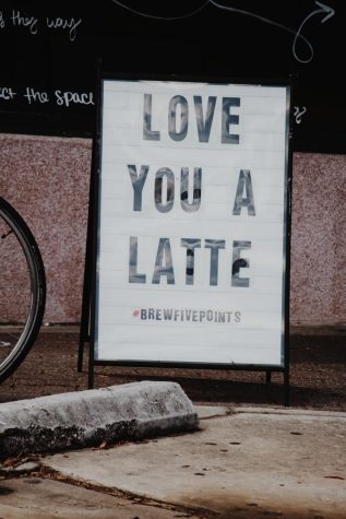  A "Love You a Latte" sign sits on a sidewalk.