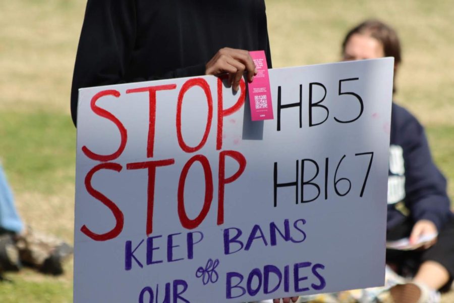 Protester holds a sign opposing HB 5 and HB 167 on the University of North Florida Green in Jacksonville, Florida, Wednesday, Feb. 16.