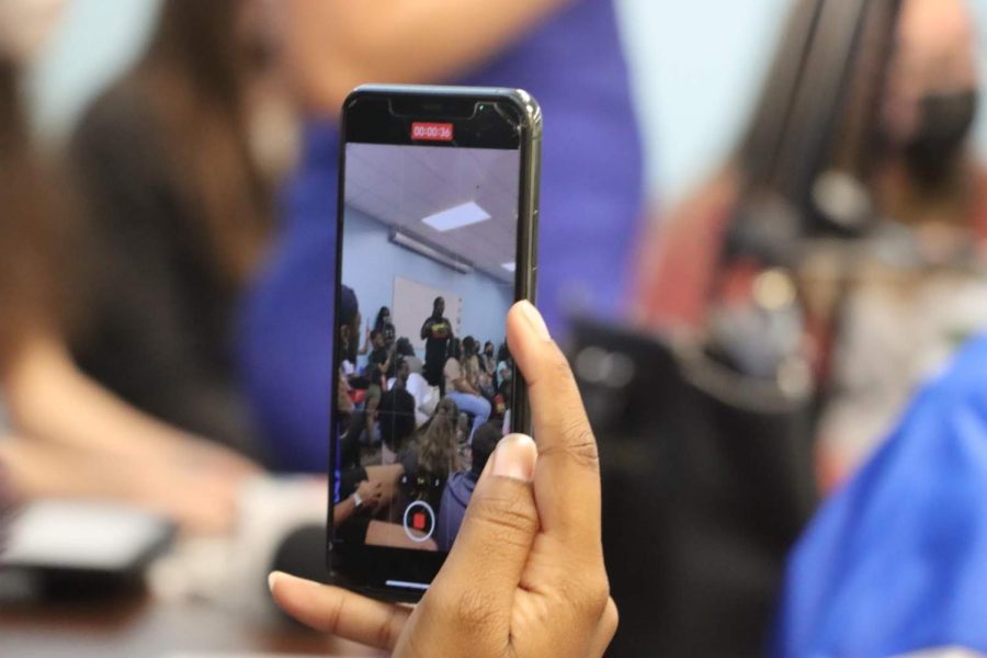 A student takes a video of another student talking about the trivia.
