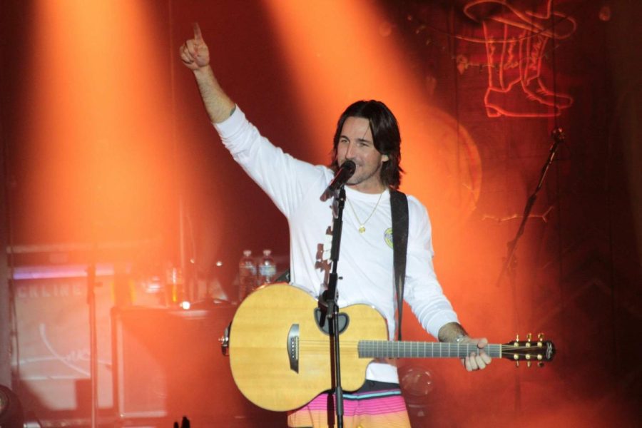 Country artist Jake Owen raises his hand and points a finger in the air during a concert performance.