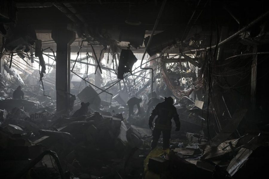 Ukrainian firefighters and servicemen search for people under debris inside a shopping center after bombing in Kyiv, Ukraine, Monday, March 21, 2022.