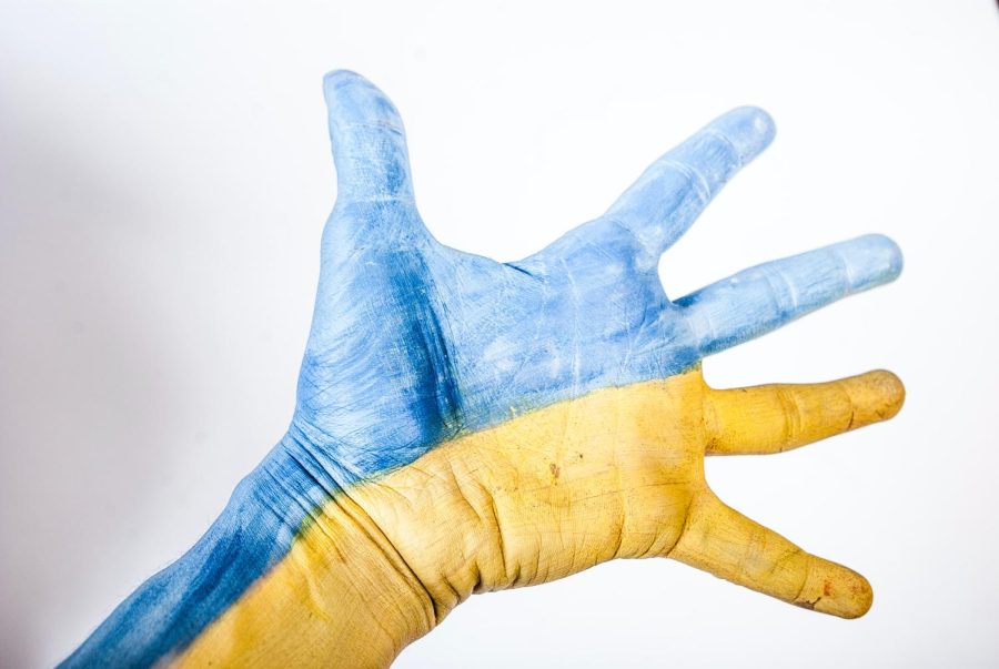 An outstretched hand painted with Ukraine’s national colors blue and yellow.