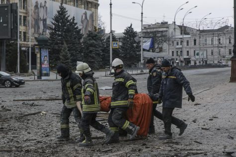Ukrainian emergency service personnel carry a body of a victim following shelling that hit the City Hall building in Kharkiv, Ukraine