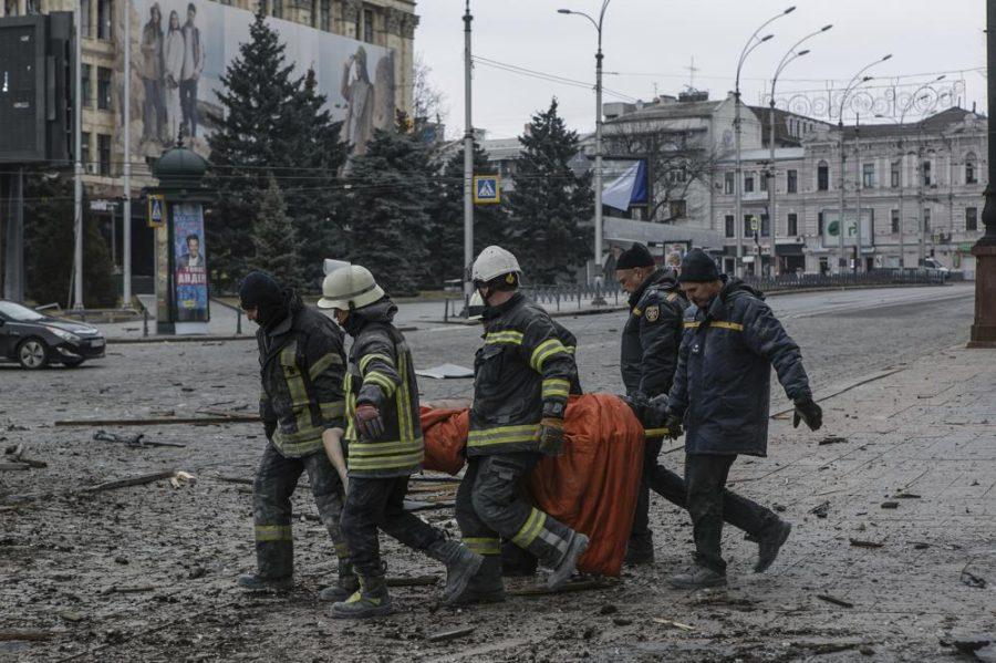 Ukrainian emergency service personnel carry a body of a victim following shelling that hit the City Hall building in Kharkiv, Ukraine