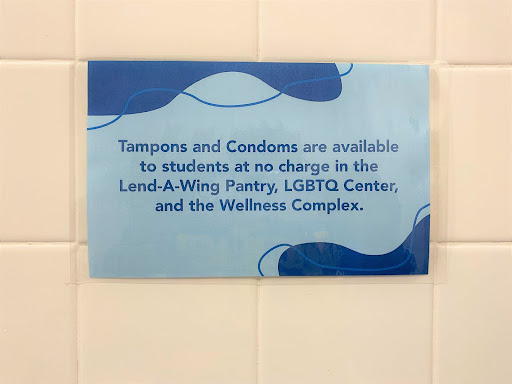 A bathroom sign explaining where to find Tampons and Condoms on campus.